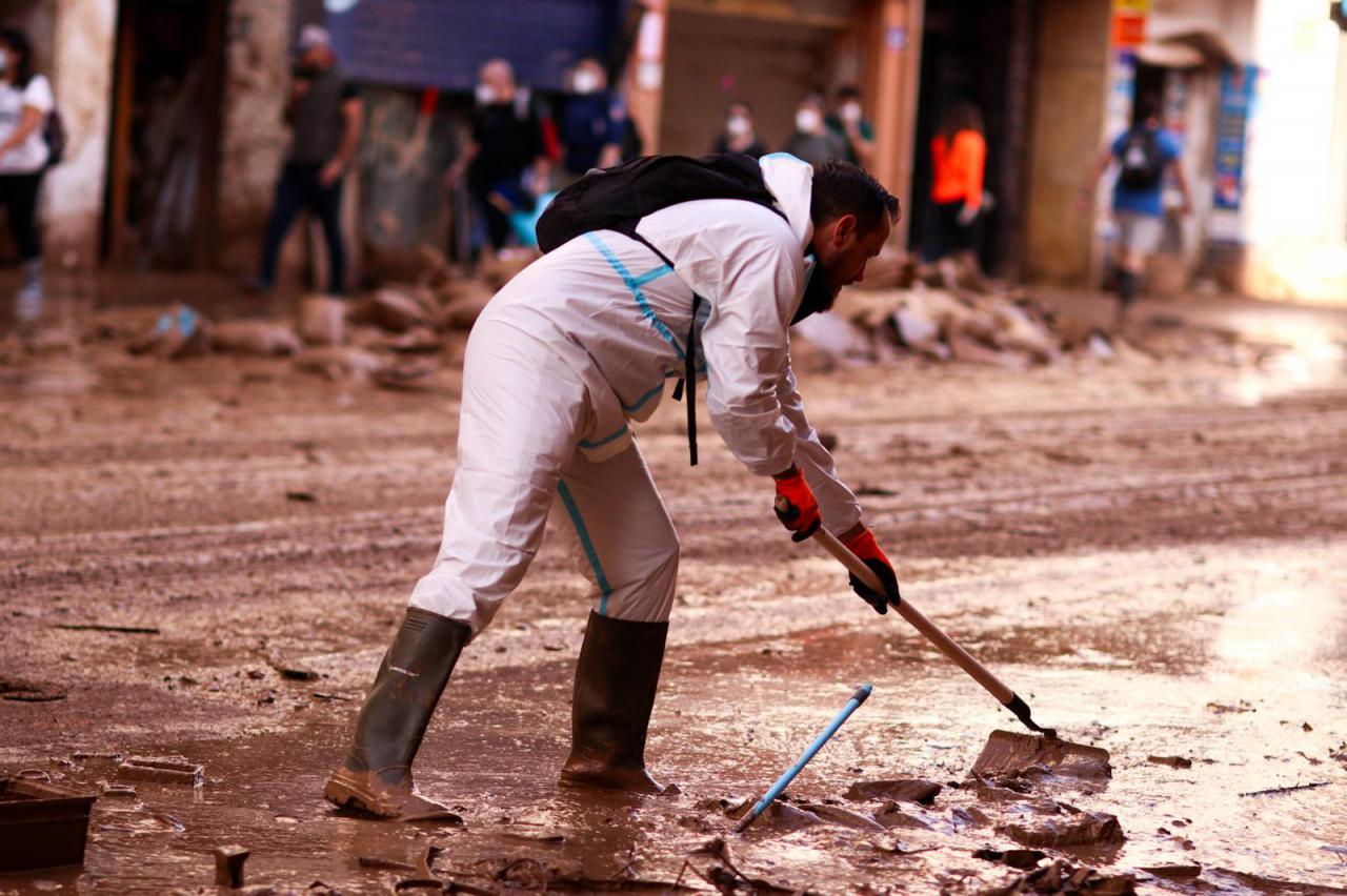 Un voluntario colabora en la limpieza de una de las calles de Benetúser cubiertas por el lodo tras el paso de la DANA en Valencia